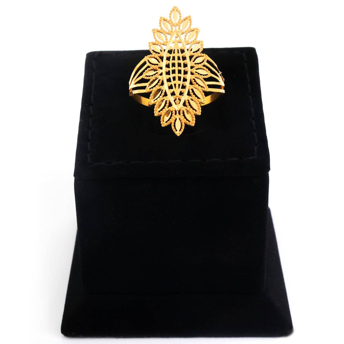 A gold ring with an intricate, symmetrical filigree design, displayed on a black velvet jewelry box against a white background.