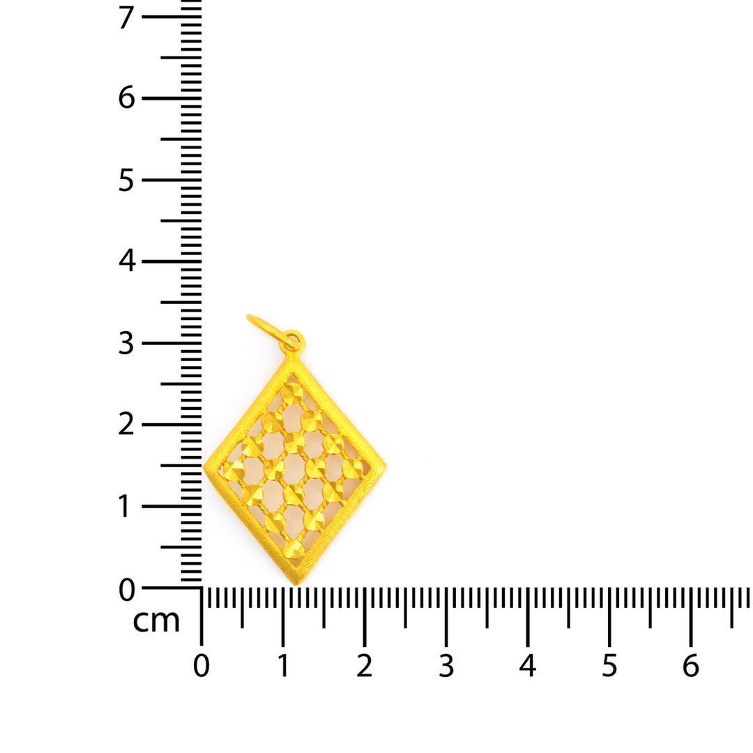 Gold pendant with cut-out design on a ruler for scale