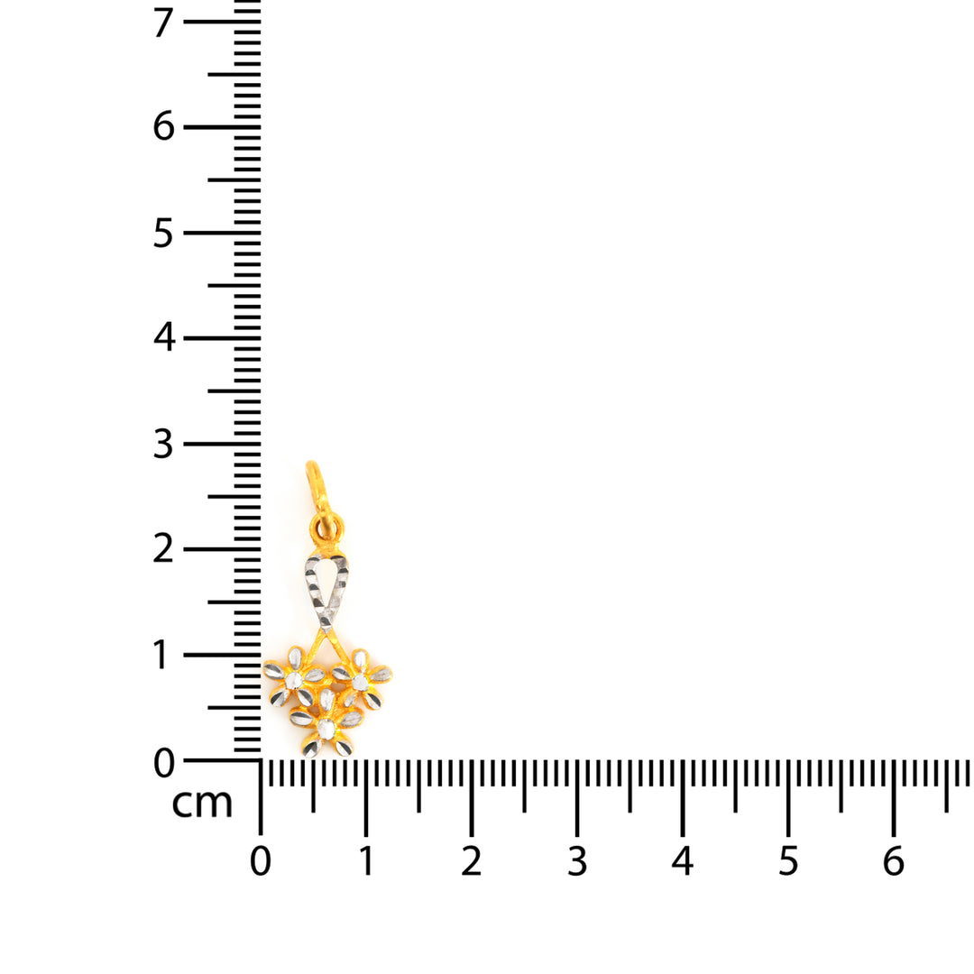 Gold and silver pendant with a ruler for scale on a white background