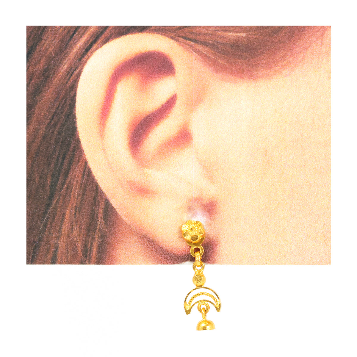 Gold earring worn on an ear with a plain background