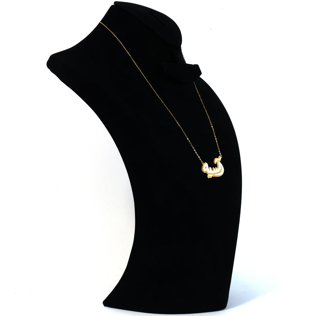 Gold necklace on a black mannequin bust against a white background