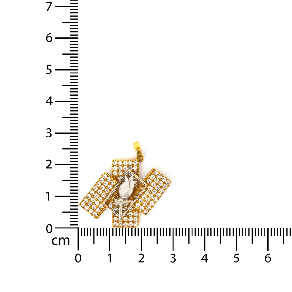 Gold rectangular pendant with clear stones on a ruler for scale