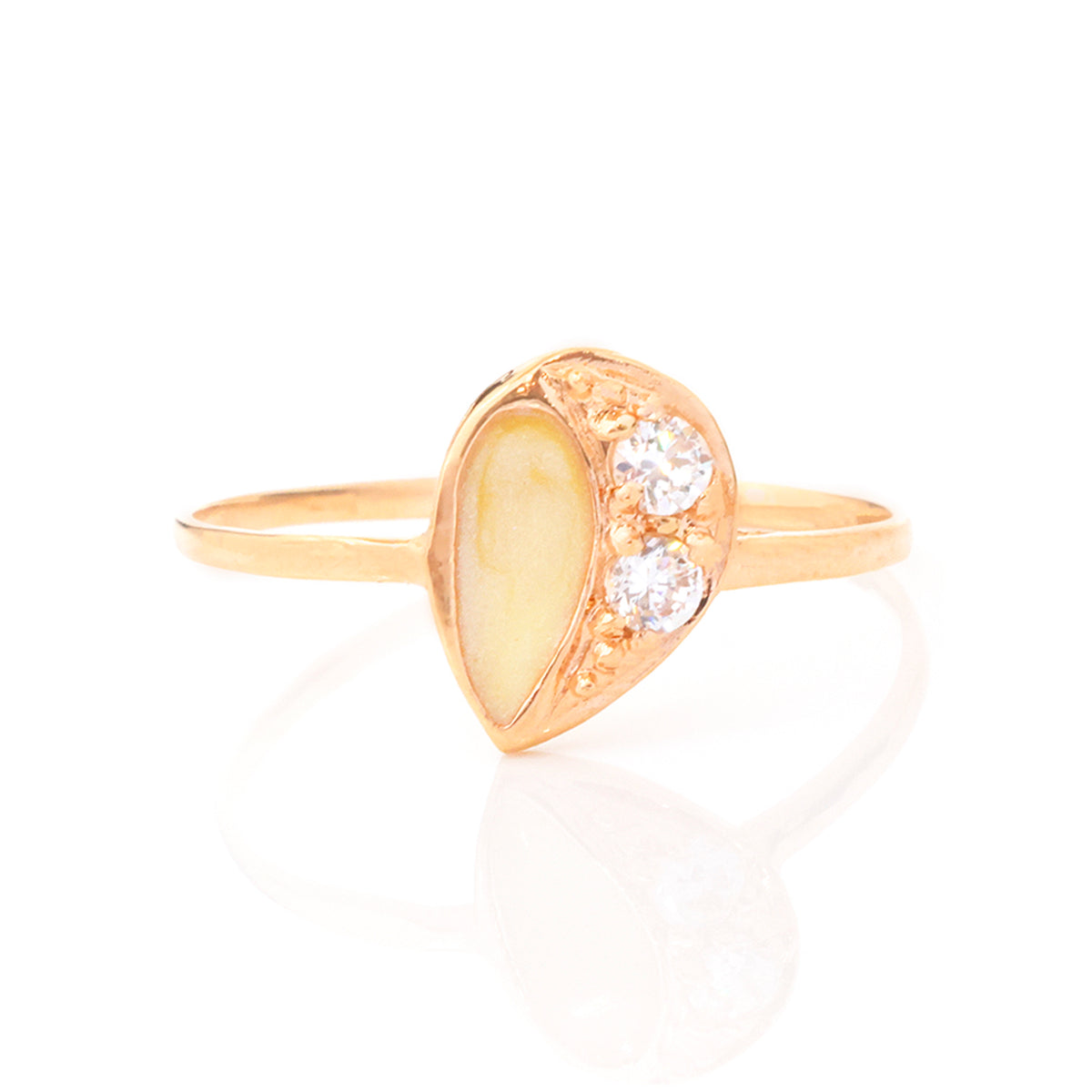 A rose gold ring featuring a teardrop-shaped yellow stone inlay on one side and three clear round-cut stones on the other, set against a clean white background with a soft reflection.