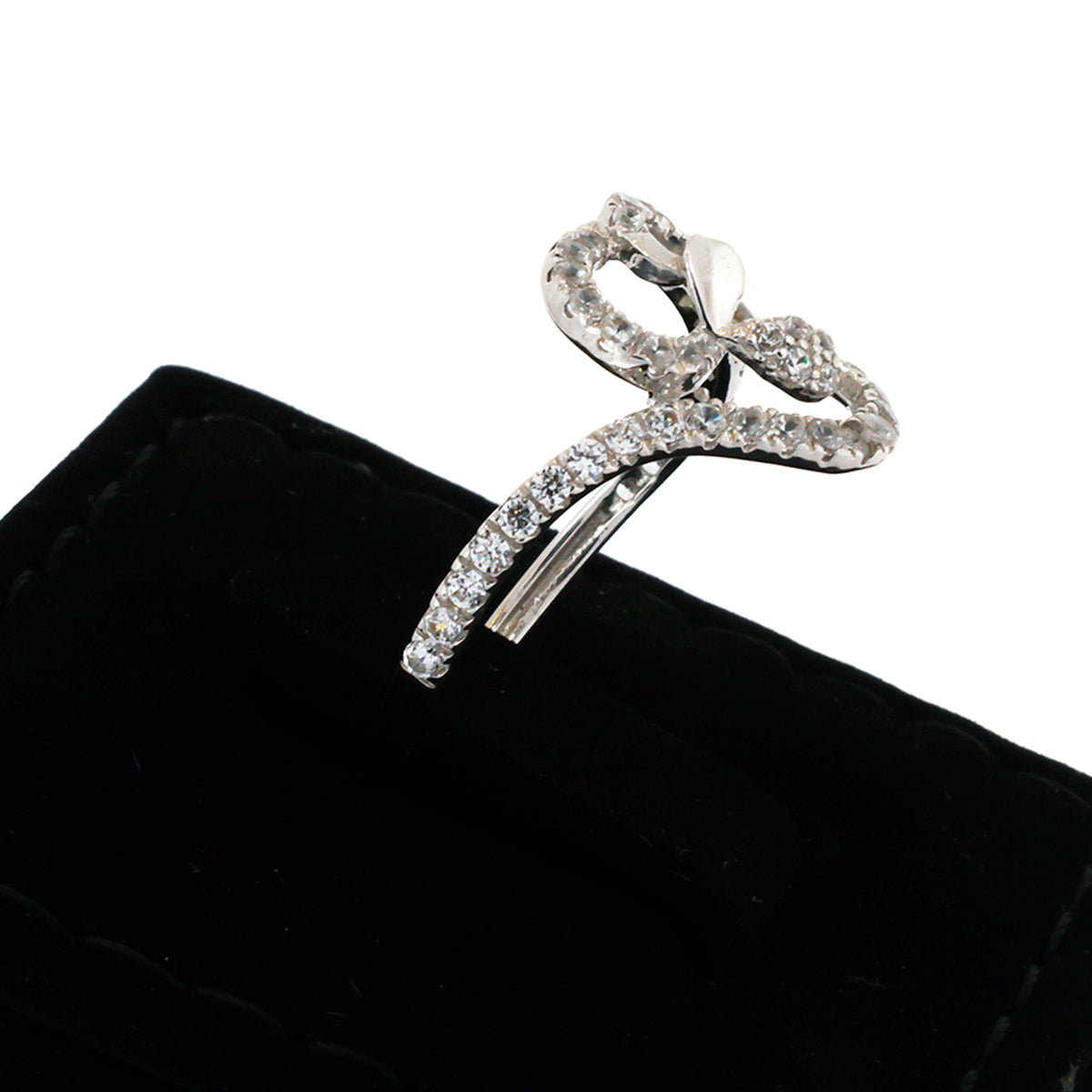 Silver bow-shaped jewelry piece on a black cushion with a white background