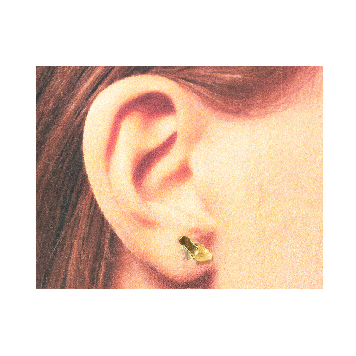 Close-up of an ear wearing a gold earring with hair partially covering the frame.