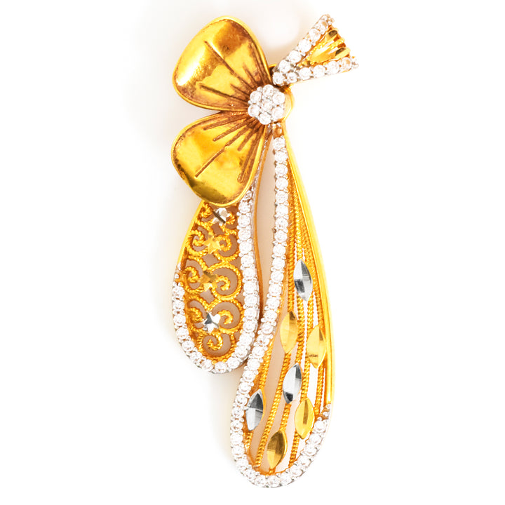 Gold bow-shaped brooch with intricate details on a white background