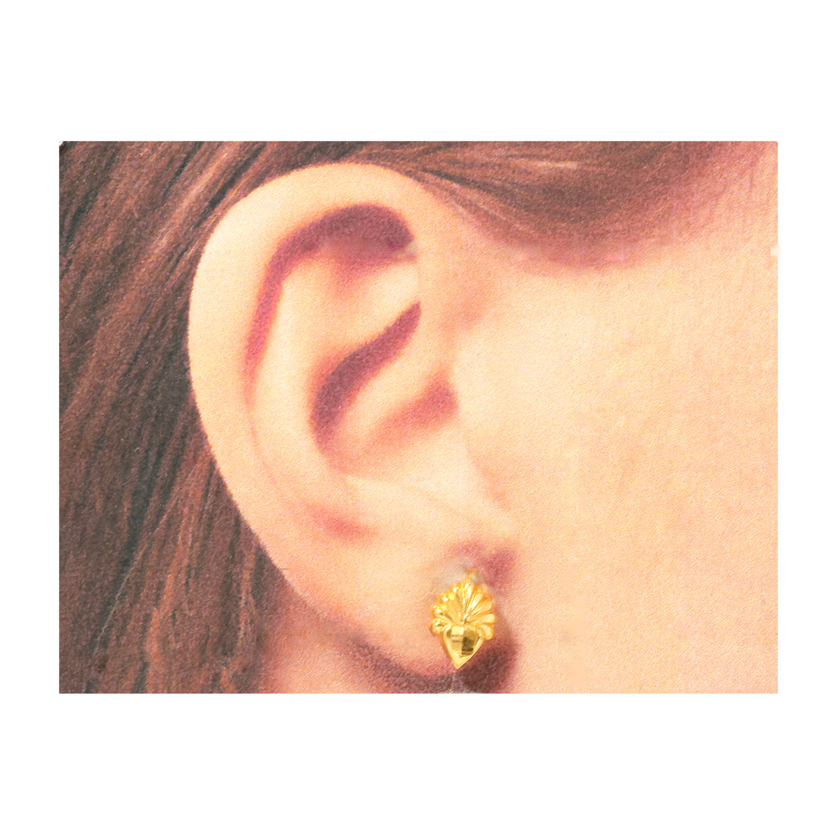 Gold earring worn by a person with brown hair.