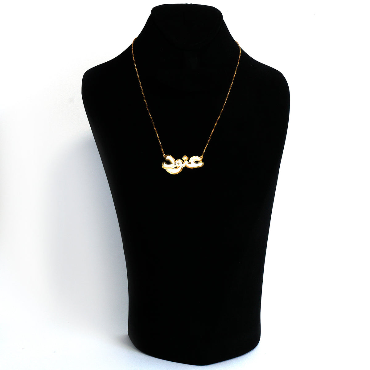Gold necklace on a black mannequin bust against a white background