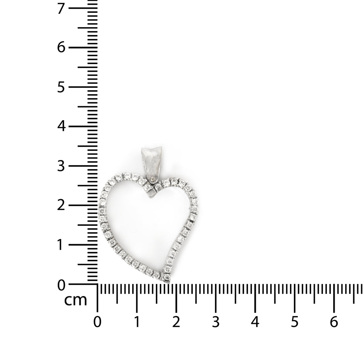 Heart-shaped diamond pendant with a ruler for scale on a white background