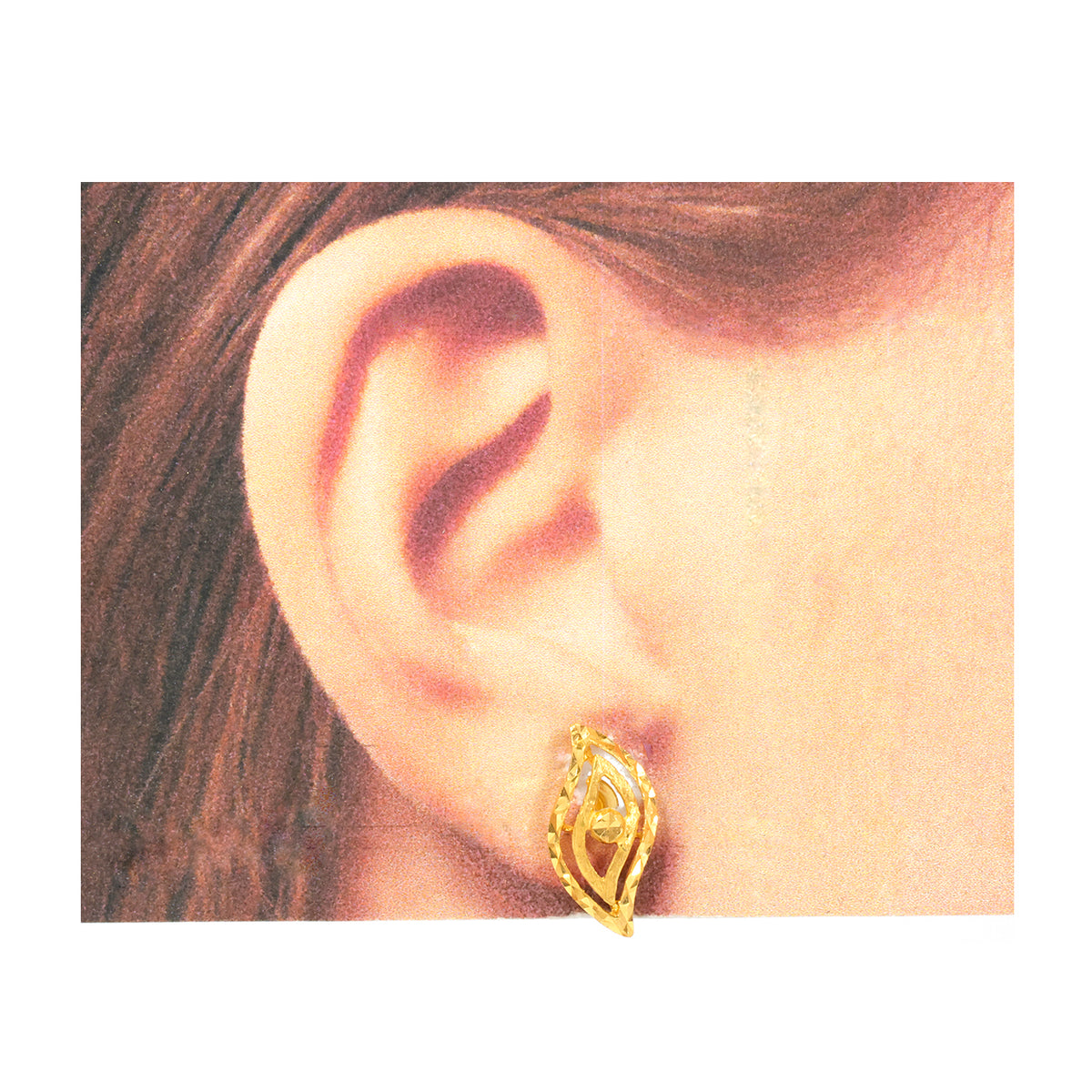 Gold earring worn on an ear with a plain background