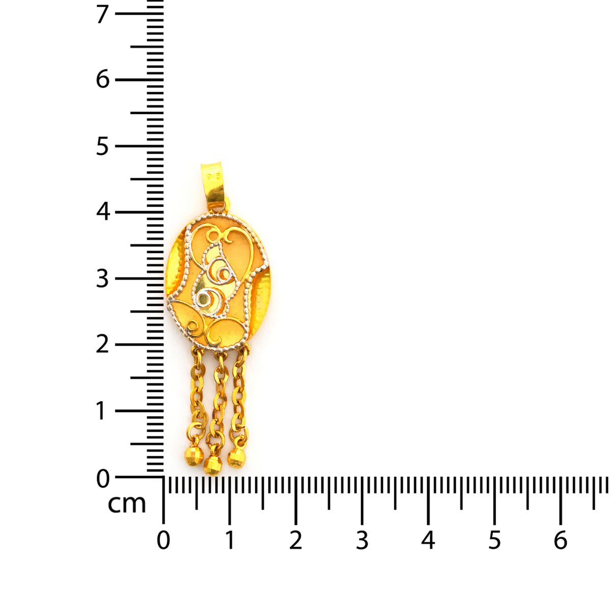 Gold pendant with chains next to a ruler for scale on a white background