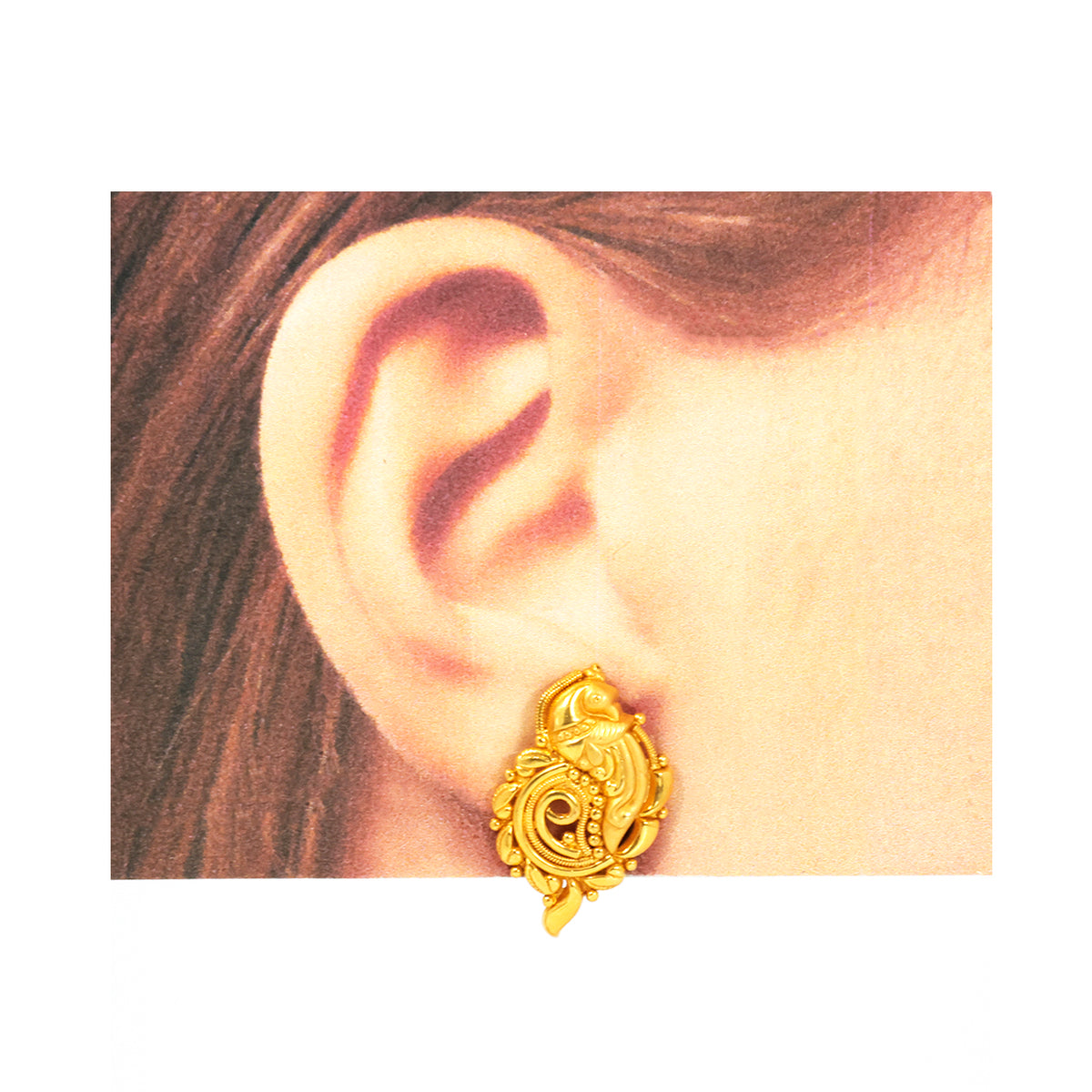 Gold earring worn on an ear with a plain background