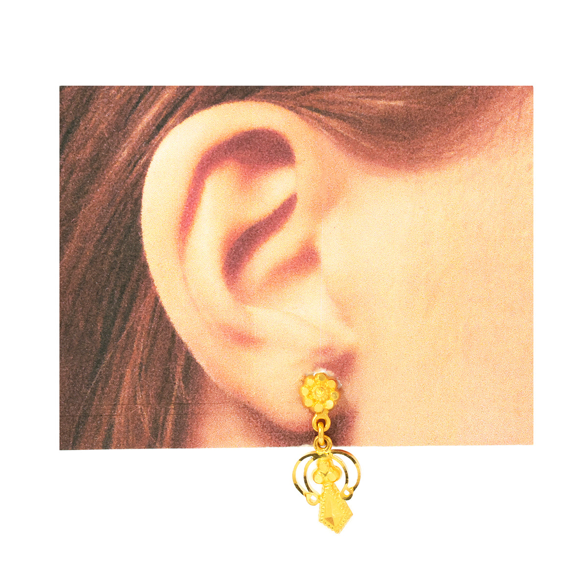 Gold earring worn on an ear with a plain background