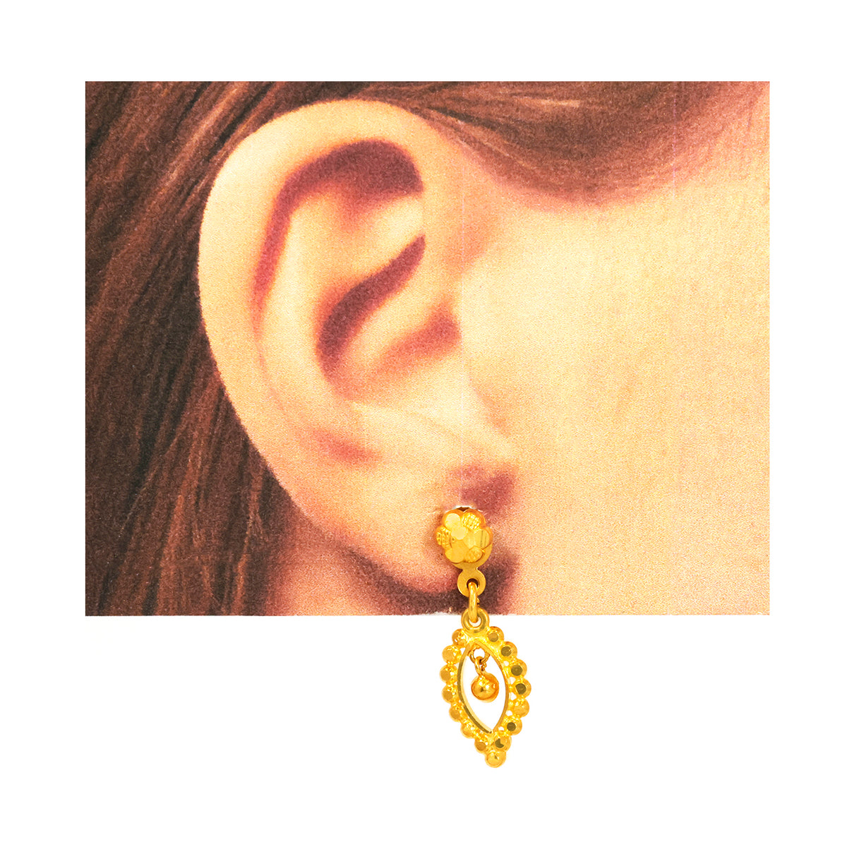 Gold earring worn on an ear with a plain background