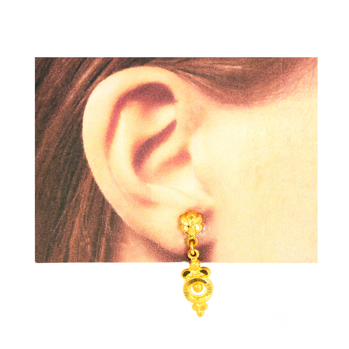 Gold earring worn on an ear with a plain background