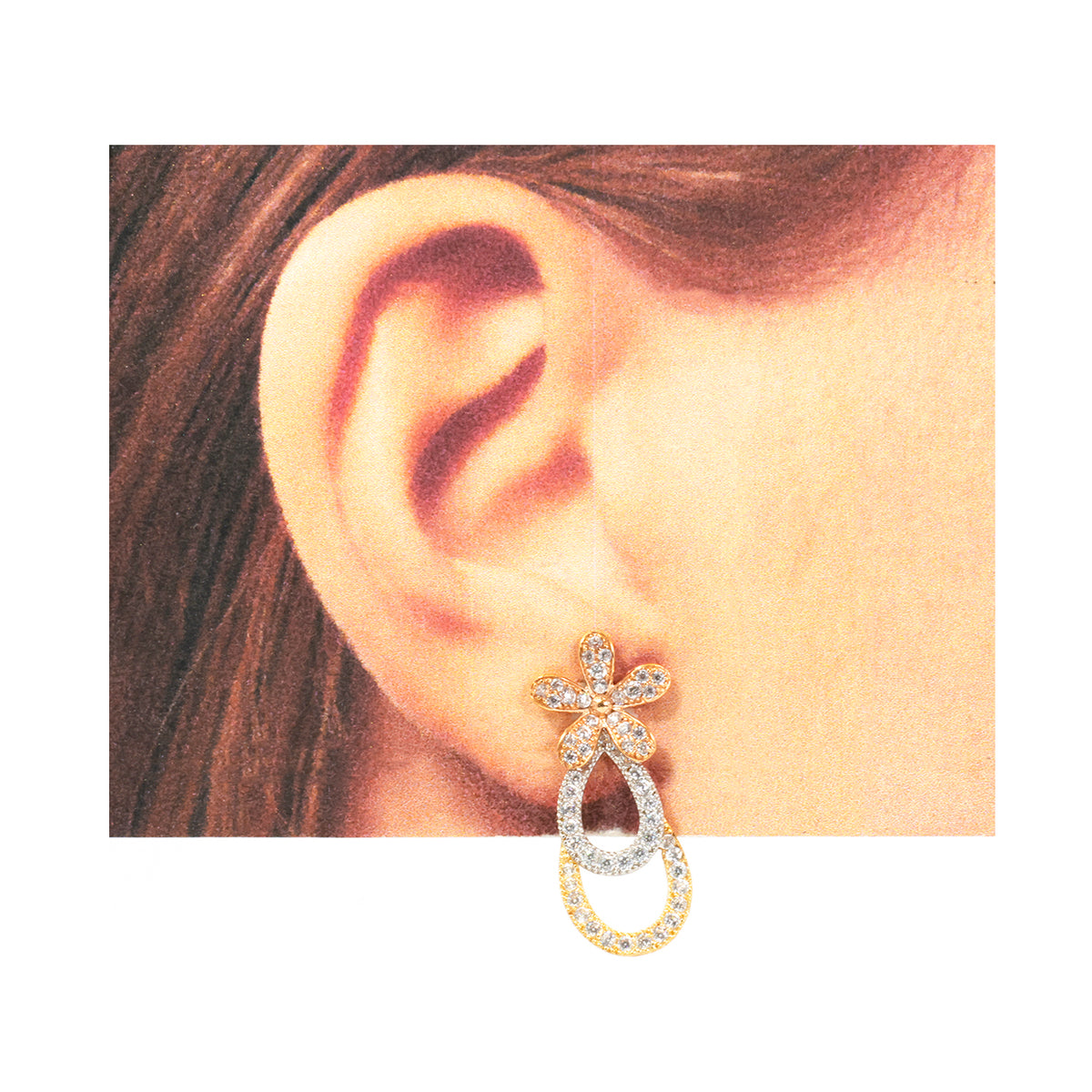 Gold and silver earring worn on an ear with a plain background