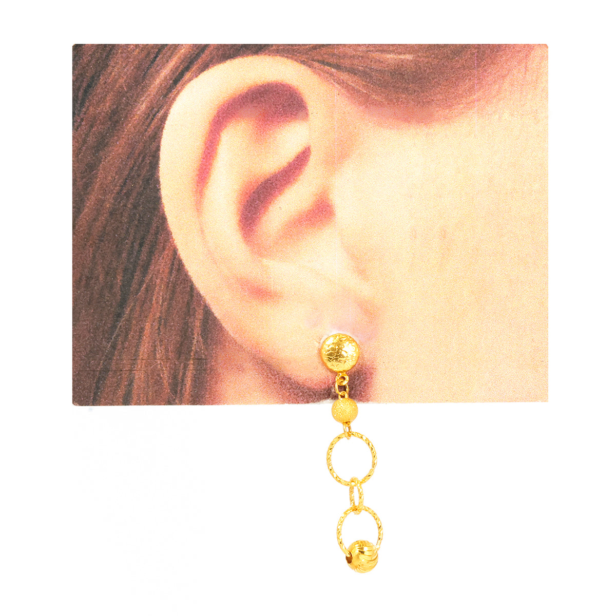 Gold earring worn on an ear with a plain background