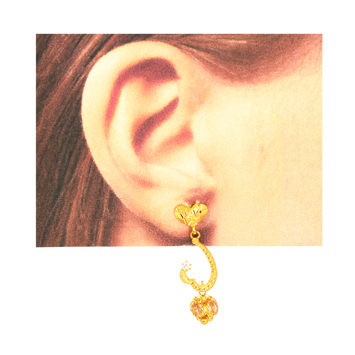 Gold earring worn on an ear with a plain background