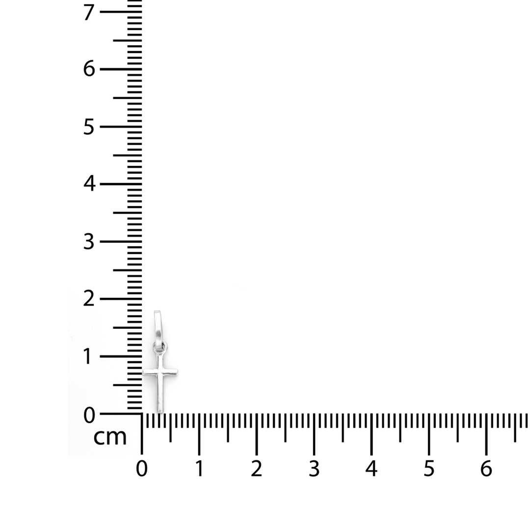 A small silver cross pendant with a halo detail, shown next to a centimeter ruler for scale on a plain white background.