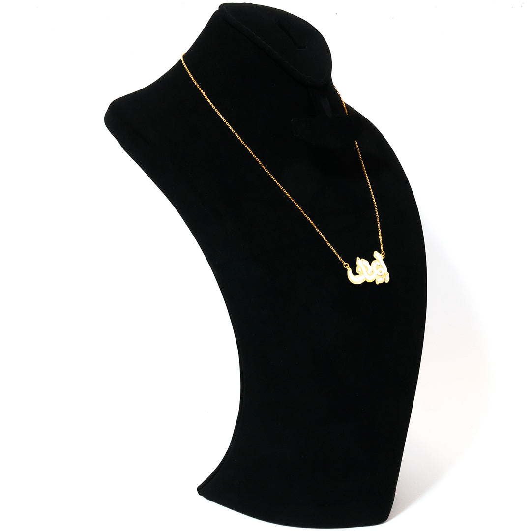 Gold necklace on a black mannequin bust against a white background