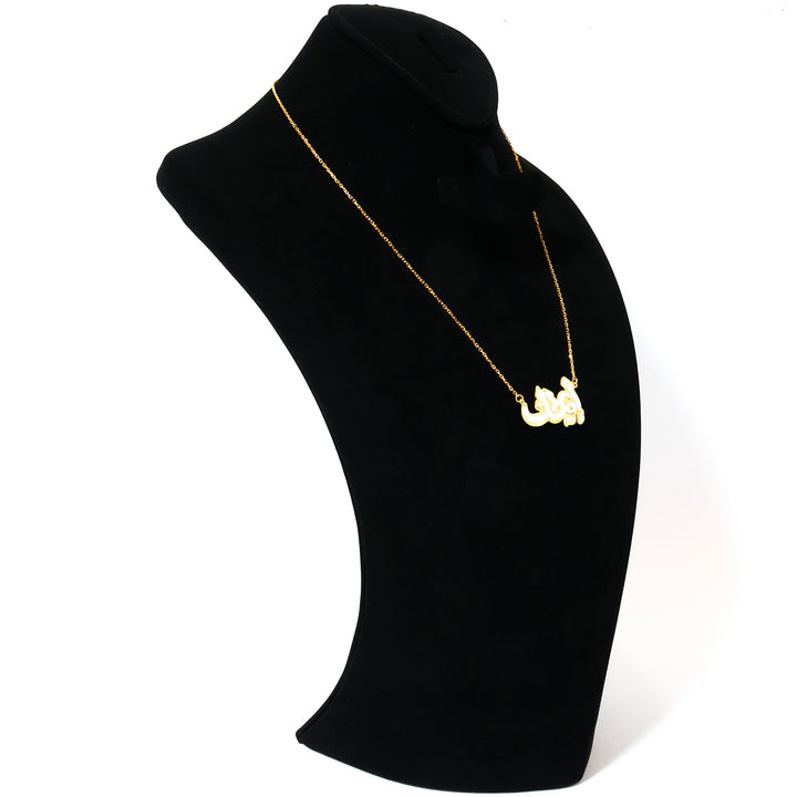 Gold necklace on a black mannequin bust against a white background