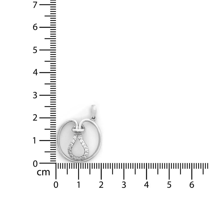 Silver pendant with a circular design on a white background with a ruler for scale.