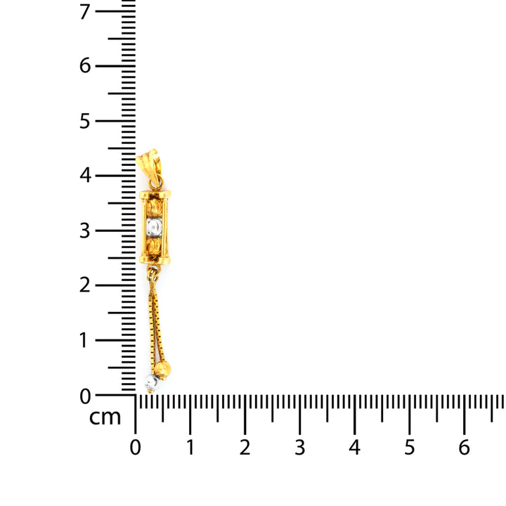 Gold pendant with a diamond measurement against a ruler on a white background