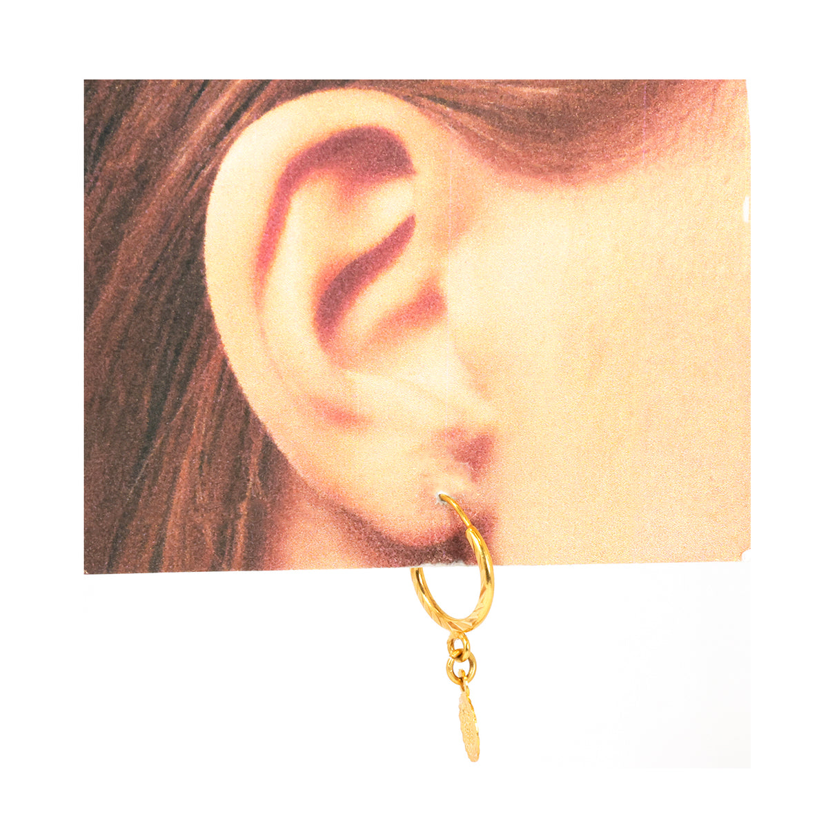 Gold hoop earring worn on an ear with a plain background