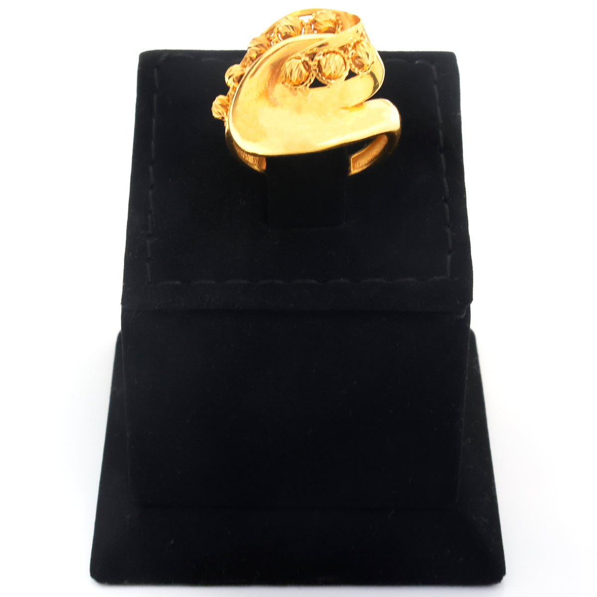 A chunky gold ring with a textured, organic wavy shape and raised circular details, displayed on a black velvet jewelry stand against a white background.