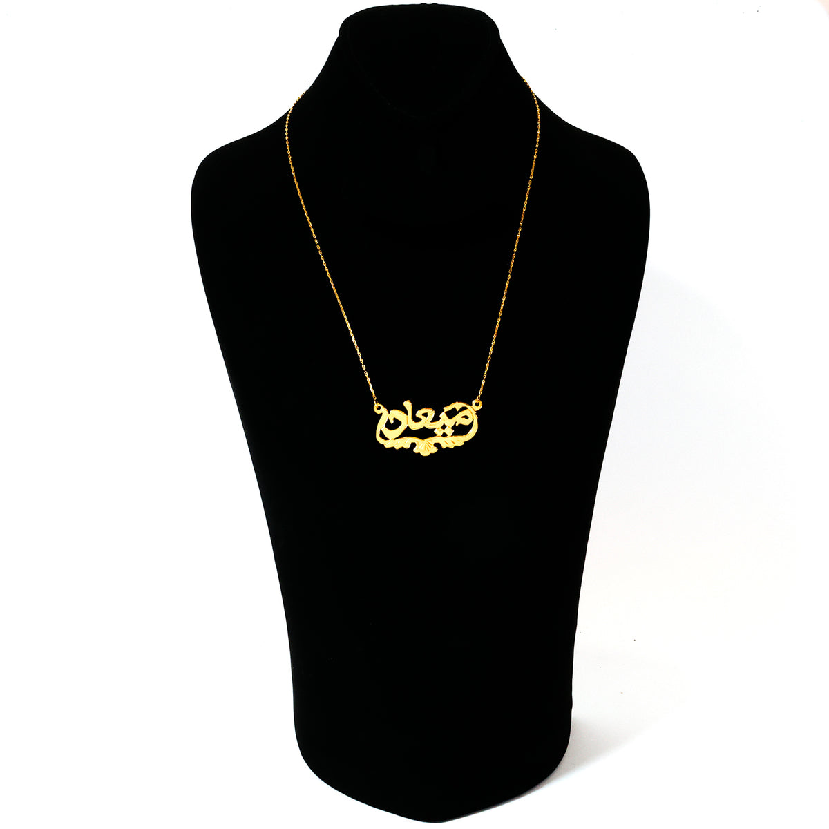 Gold necklace on a black mannequin bust against a white background