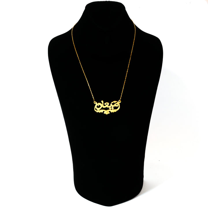 Gold necklace on a black mannequin bust against a white background