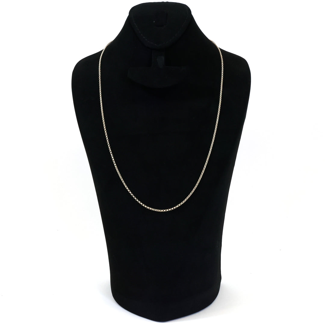 Gold chain necklace on a black mannequin bust against a white background