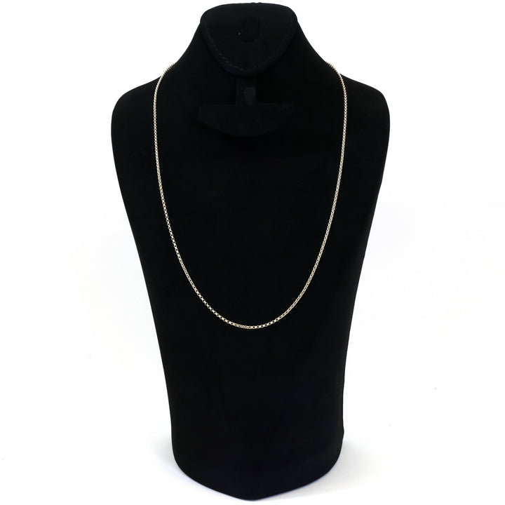 Gold chain necklace on a black mannequin bust against a white background