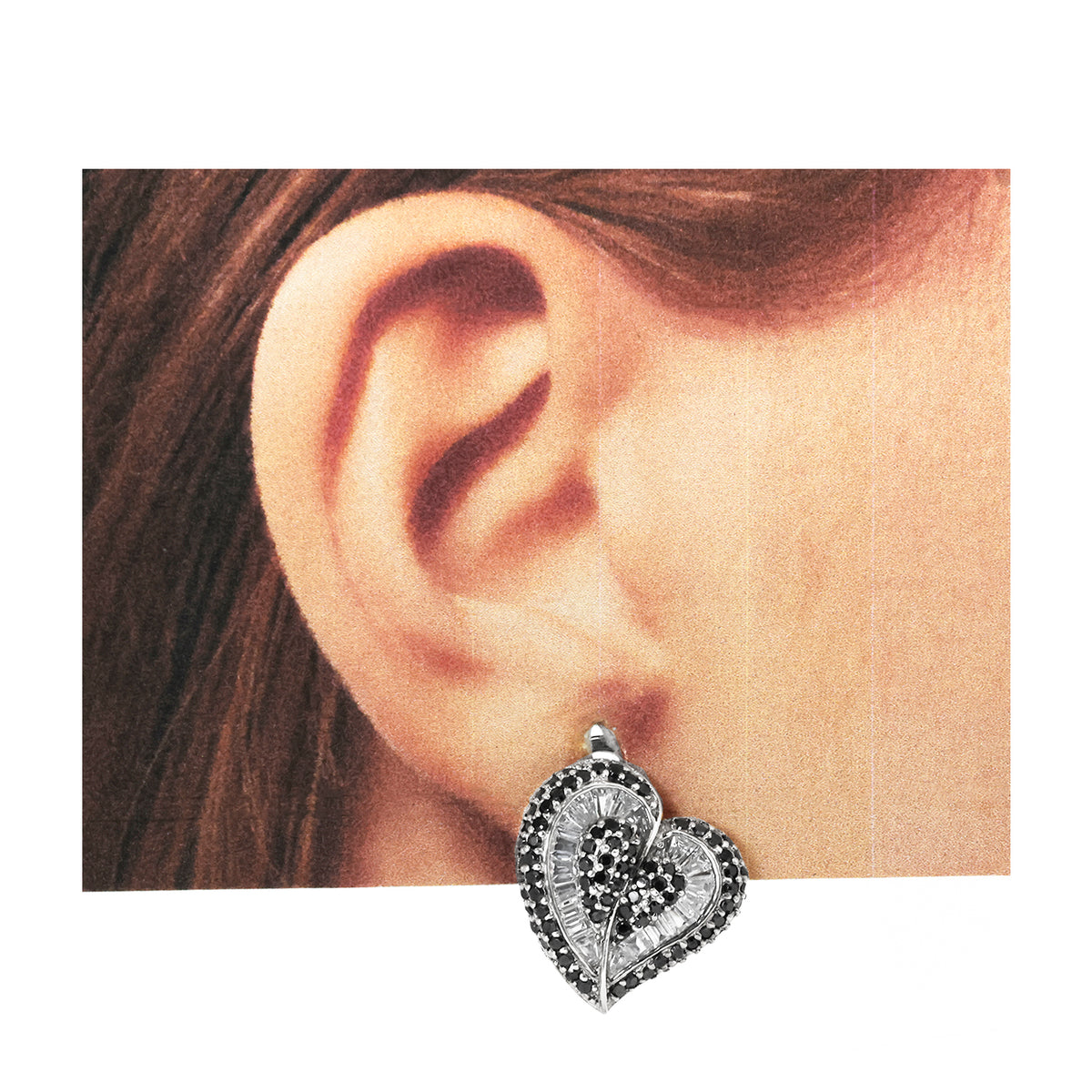 Heart-shaped earring worn on an ear with a plain background