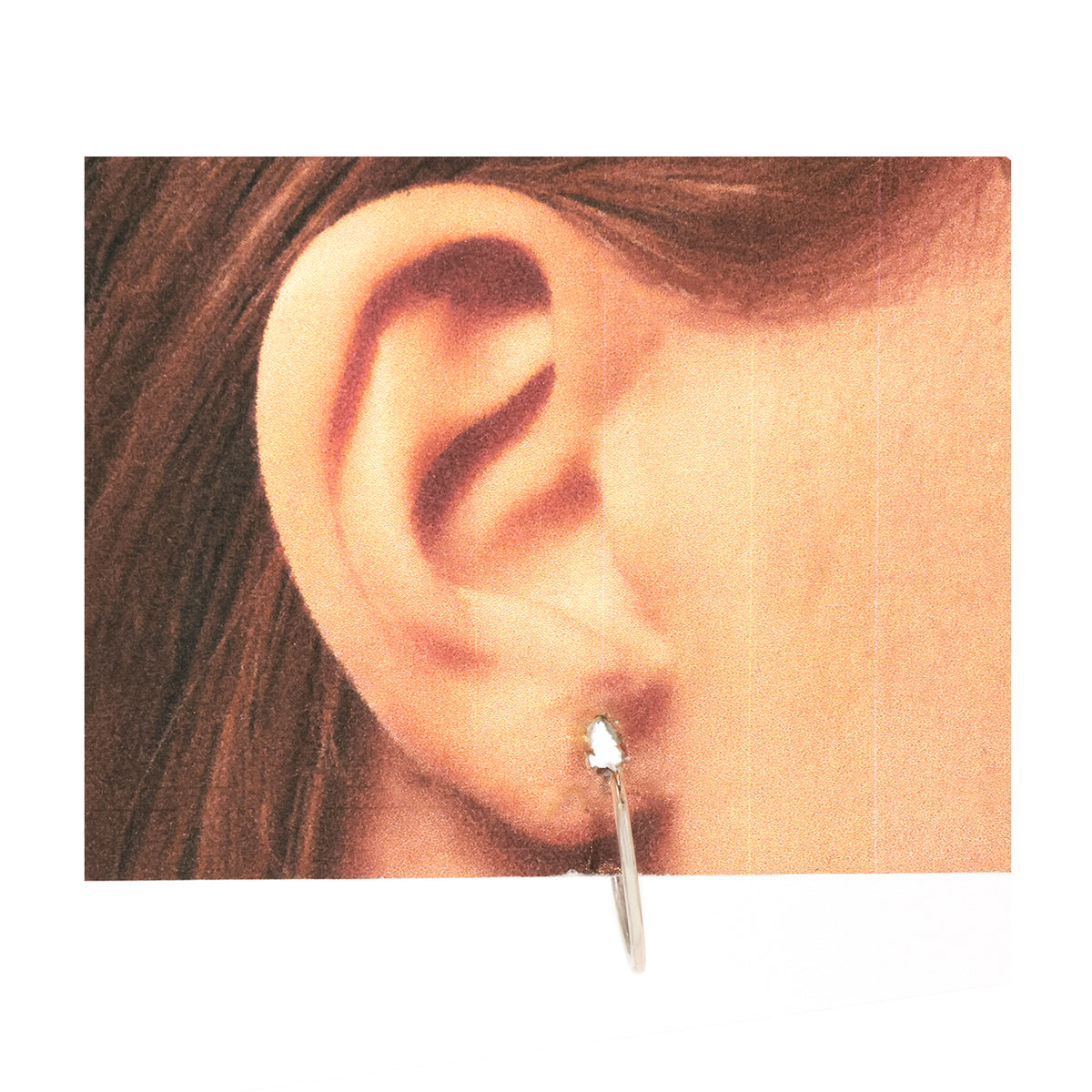 Close-up of an ear with a silver earring on a white background