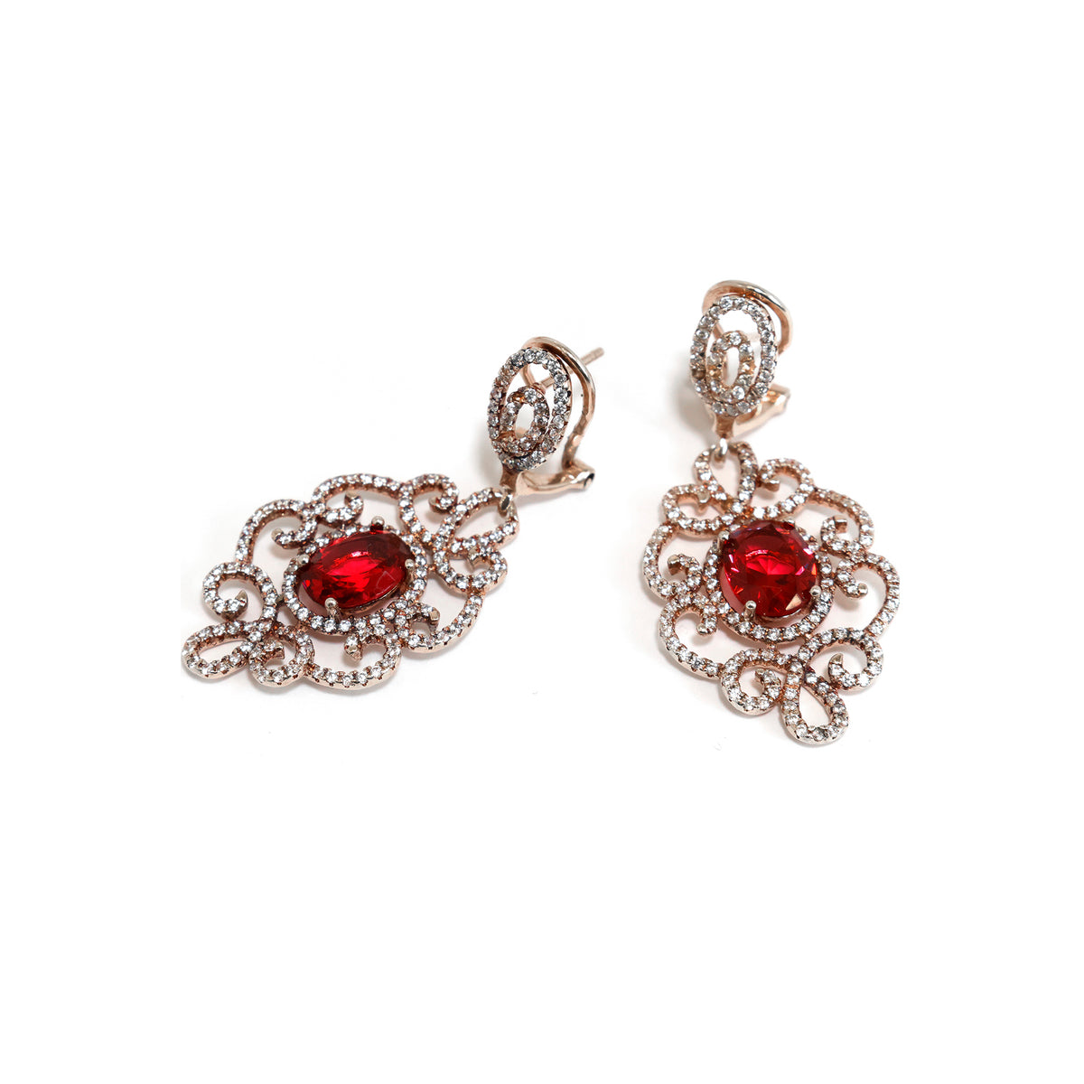 Pair of ornate earrings with red gemstones on a white background
