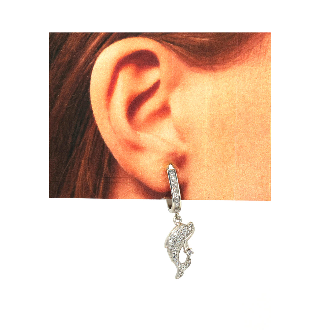 Silver hoop earring with a dangling charm worn by a person