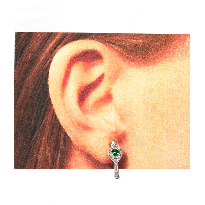 Close-up of an ear wearing a green gemstone earring with a white background
