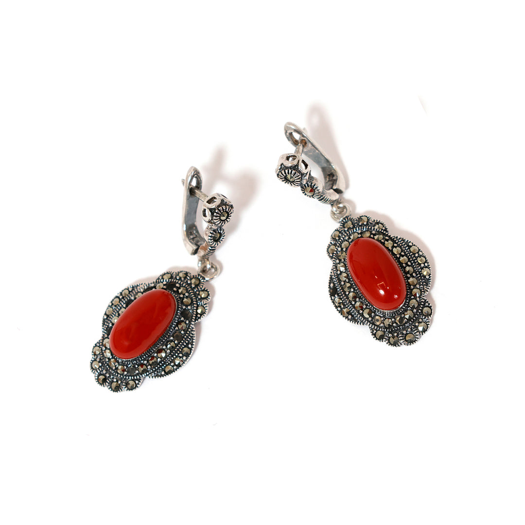 Pair of silver earrings with red stones on a white background