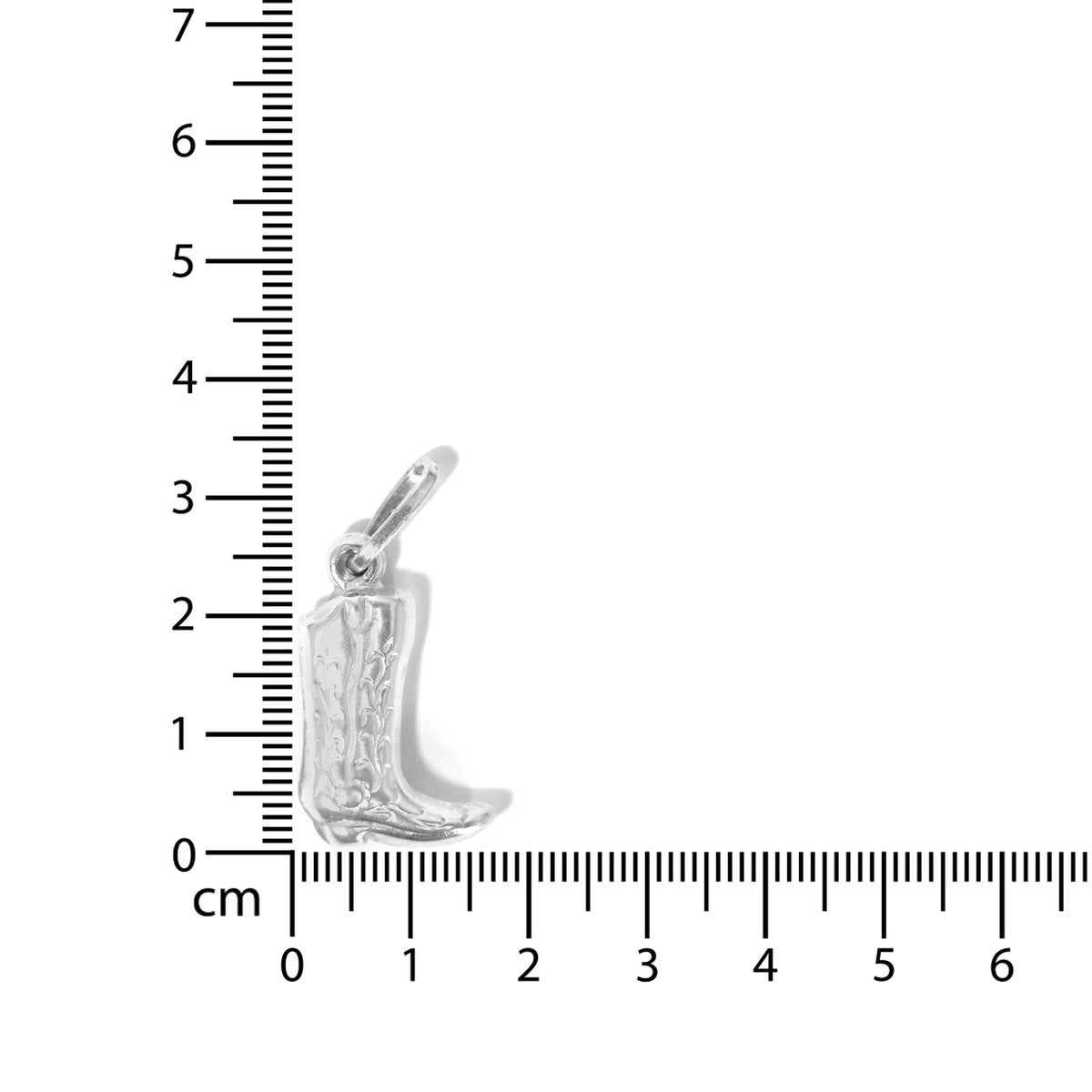Silver cowboy boot charm next to a ruler for scale on a white background