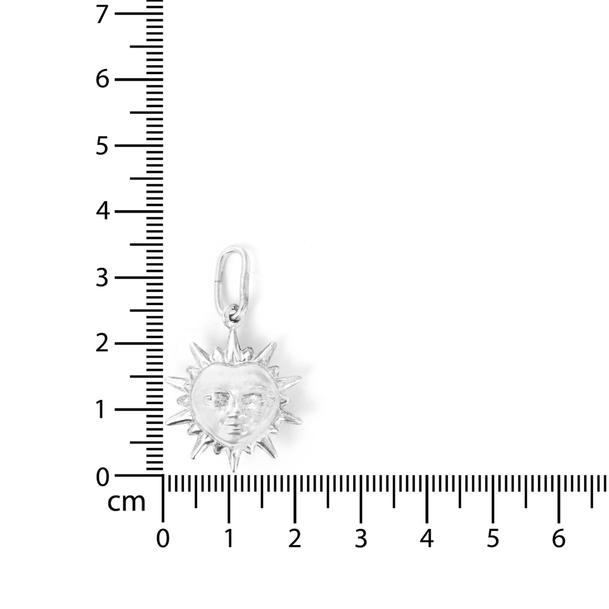 Silver sun pendant with face measurement against a ruler on a white background