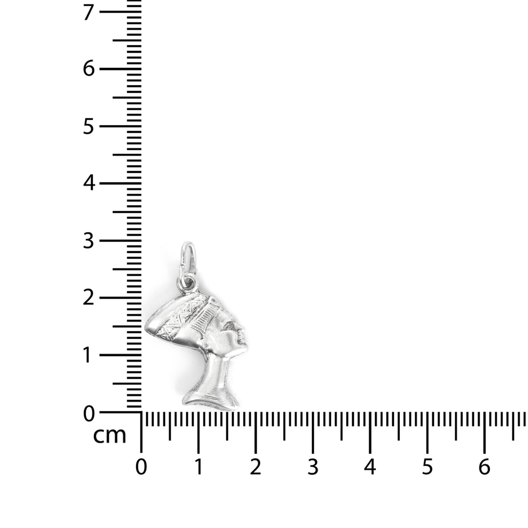 Silver horse head pendant next to a ruler on a white background