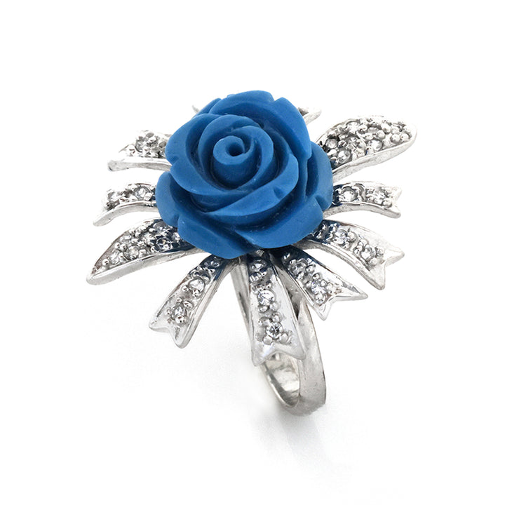 Silver ring with a blue rose and clear stones on a white background
