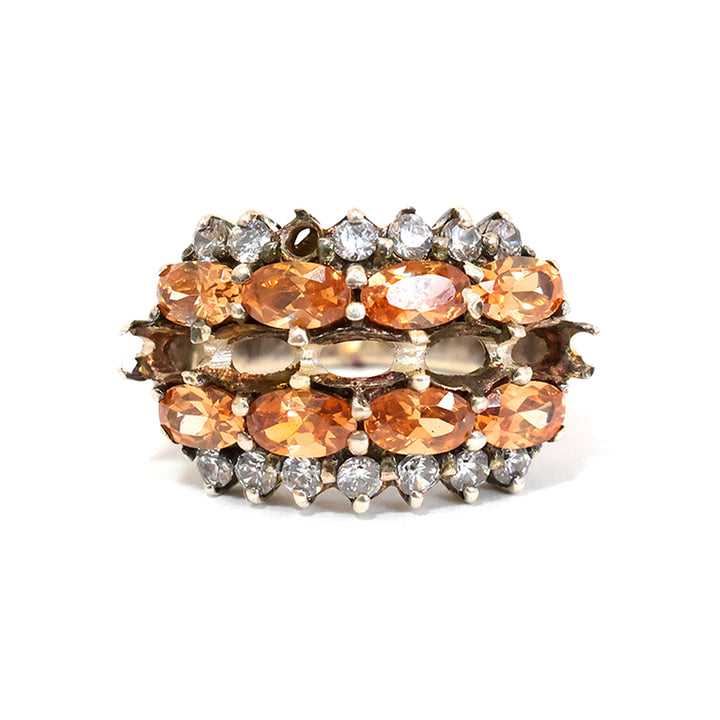 Jewelry ring with orange and clear gemstones on a white background